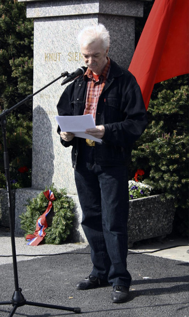 Ingar Knudtsen holder 1. mai-tale i Kristiansund, foran et monument med rød fane